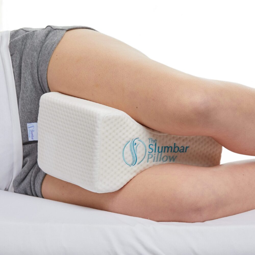 Knee pillow being used by a side sleeper on a white bed
