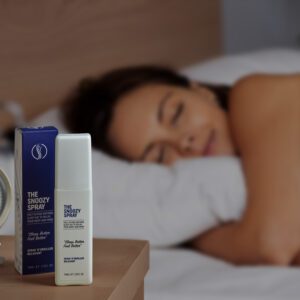 Image showing The Snoozy Spray bottle and the box next to bed with beautiful women in the background sleeping