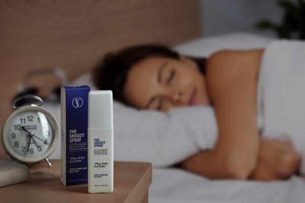 Image showing The Snoozy Spray bottle and the box next to bed with beautiful women in the background sleeping
