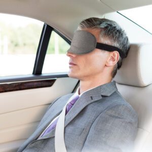 Mature businessman napping while wearing eye mask in car