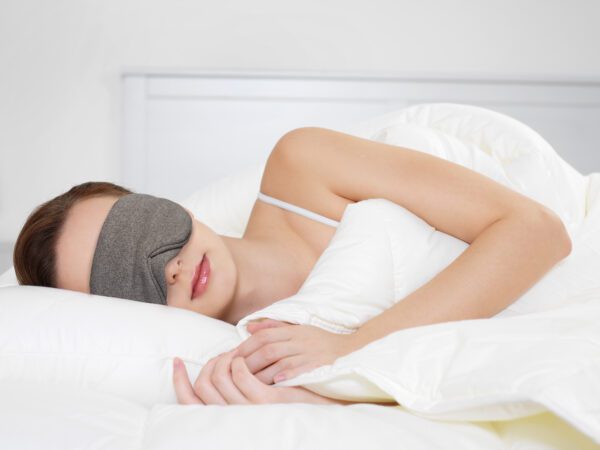 Young beautiful woman sleeping lying on the side in the bedroom and wearing a Slumbar eye mask