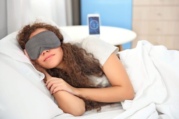 Beautiful girl sleeping in bed wearing a Slumbar eye mask