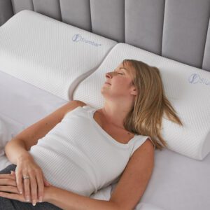 Orthopaedic neck pillow displayed on a bed with a young women sleeping