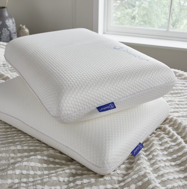 Two Slumbar Memory foam pillows at a slight angle stacked on top of each other in a bedroom