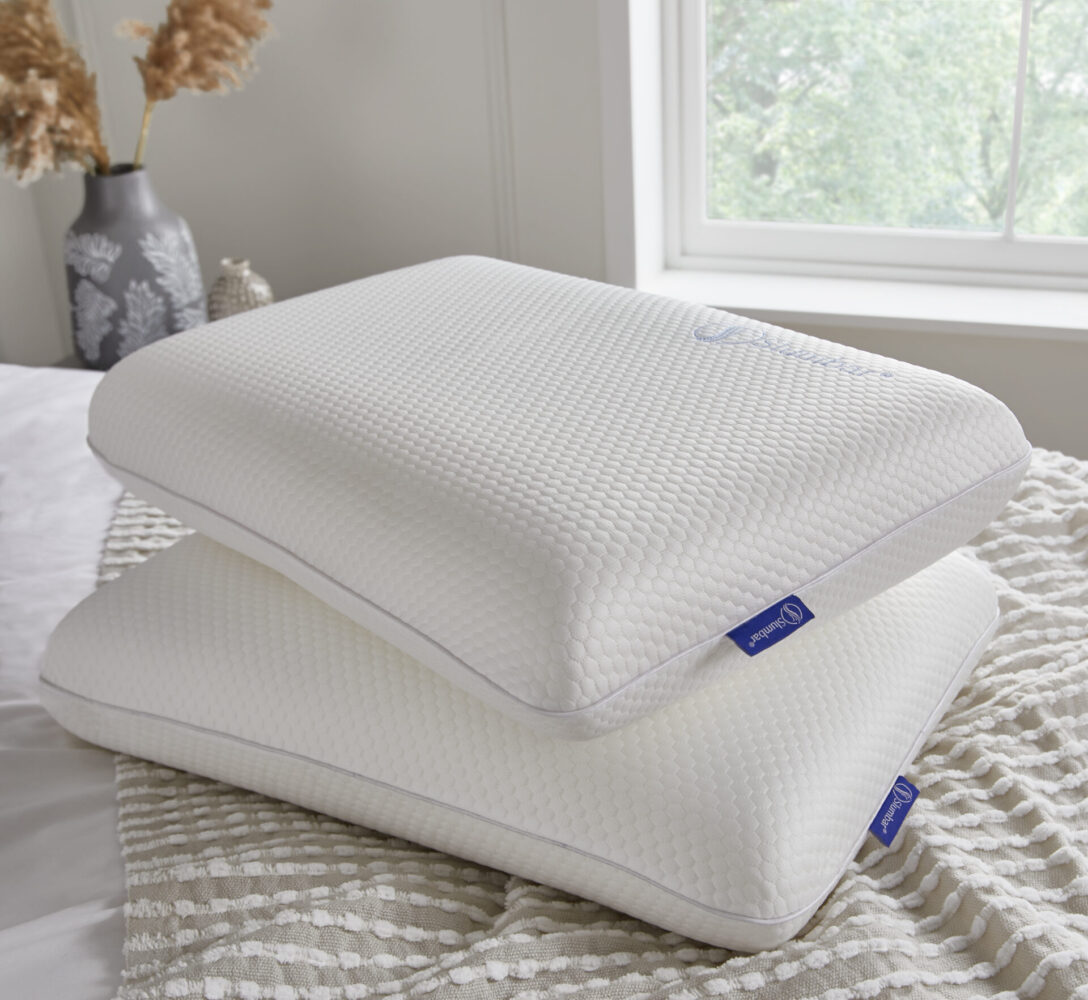 Two Slumbar Memory foam pillows stacked on top of each other in a bedroom