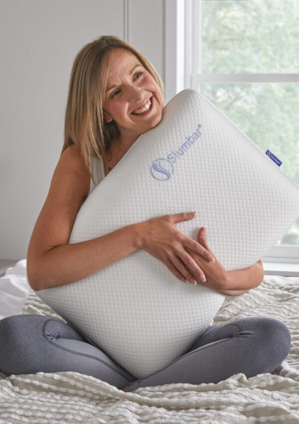 Luxury Memory foam pillow by slumbar being held by a model on a bed